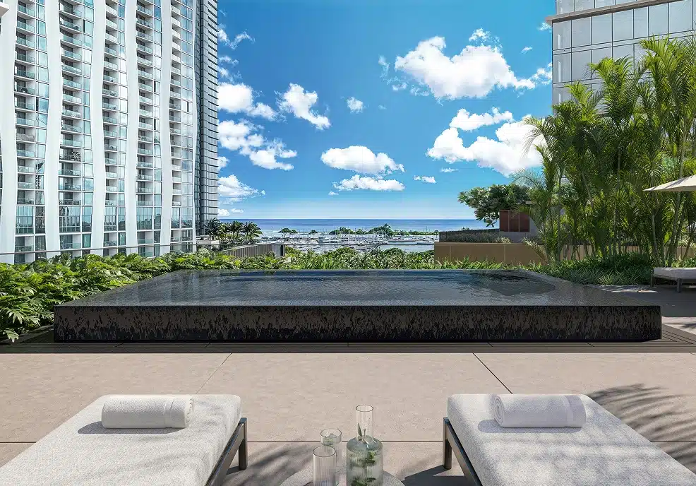 Modern outdoor infinity pool with two lounge chairs, city high-rise buildings, palm trees, and a clear blue sky with scattered clouds in the background.