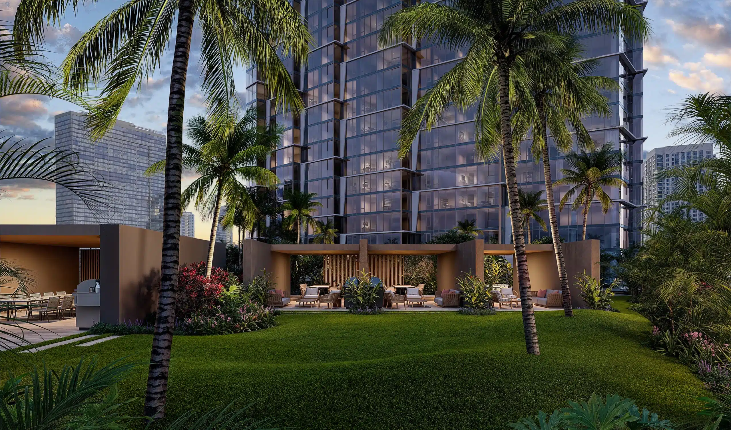 Lush garden area with palm trees, modern outdoor seating, and a high-rise glass building in the background under a partly cloudy sky.