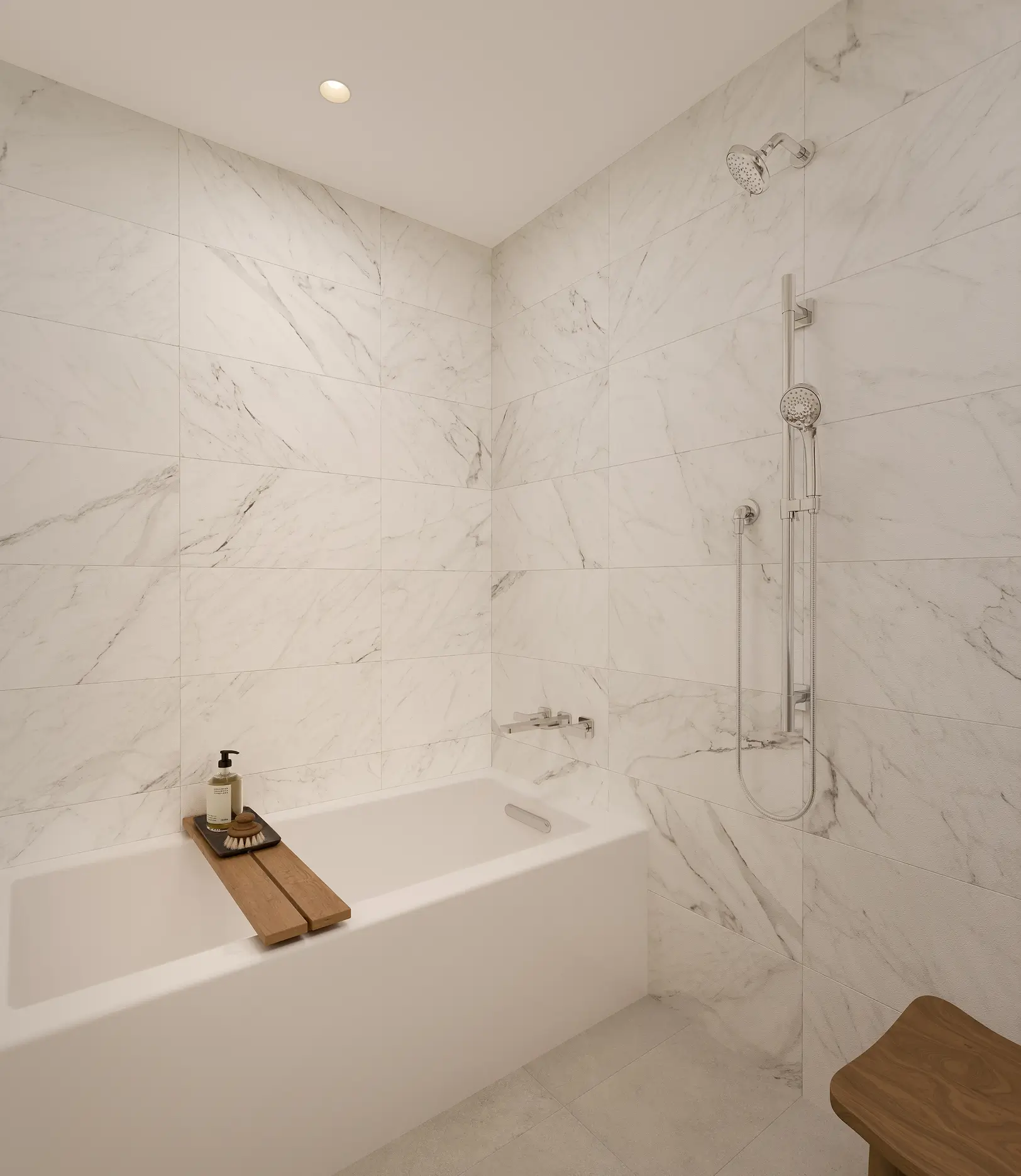 Modern bathroom with white marble tiles, built-in bathtub, wooden bath tray with soap and brush, wall-mounted shower, and a wooden stool.