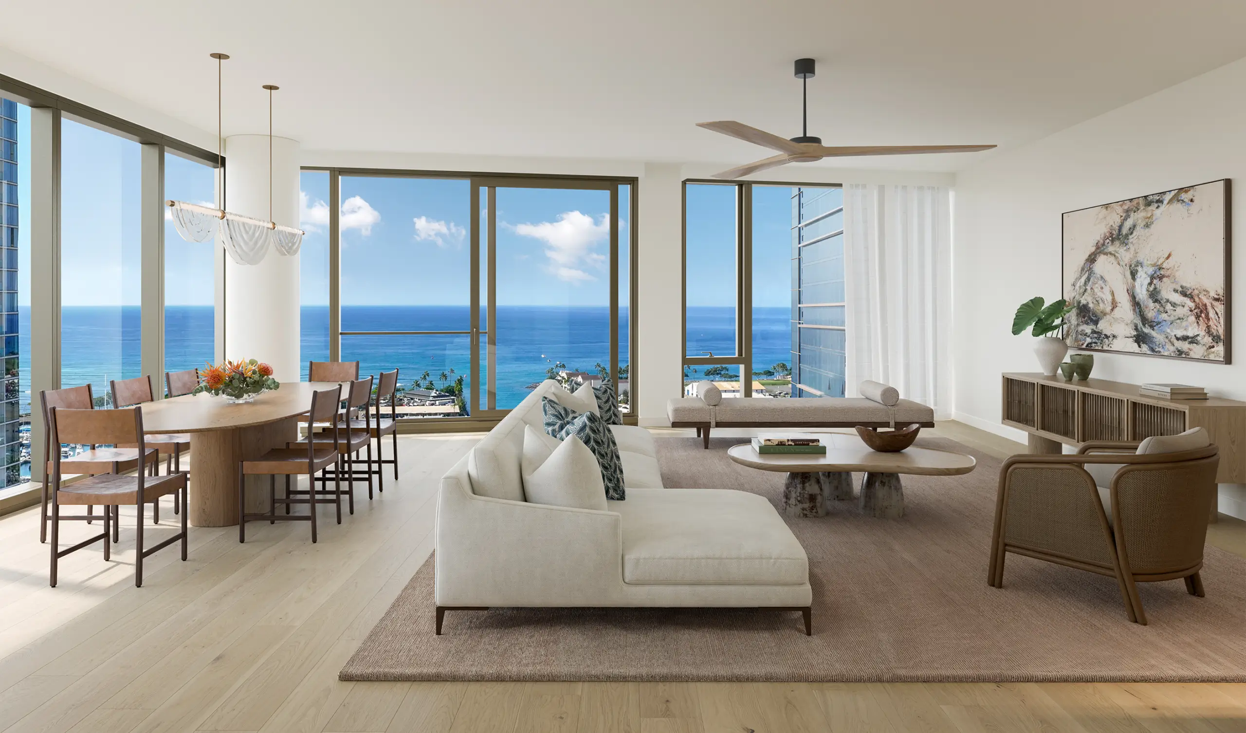 Modern living and dining area with light wood floors, neutral furniture, large windows, and ocean views under a clear sky.