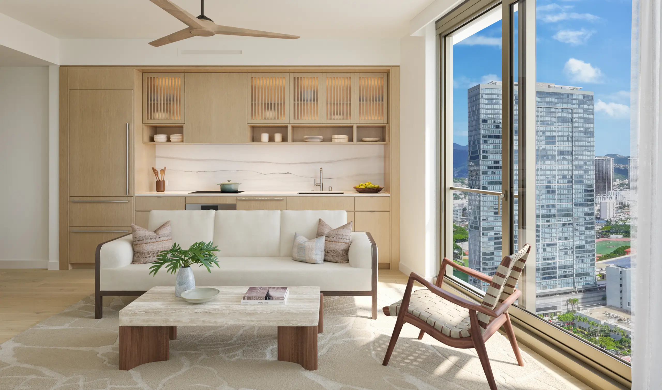 Modern living room with a white sofa, marble coffee table, and wooden accents, adjacent to a kitchen and large window overlooking city buildings on a sunny day.