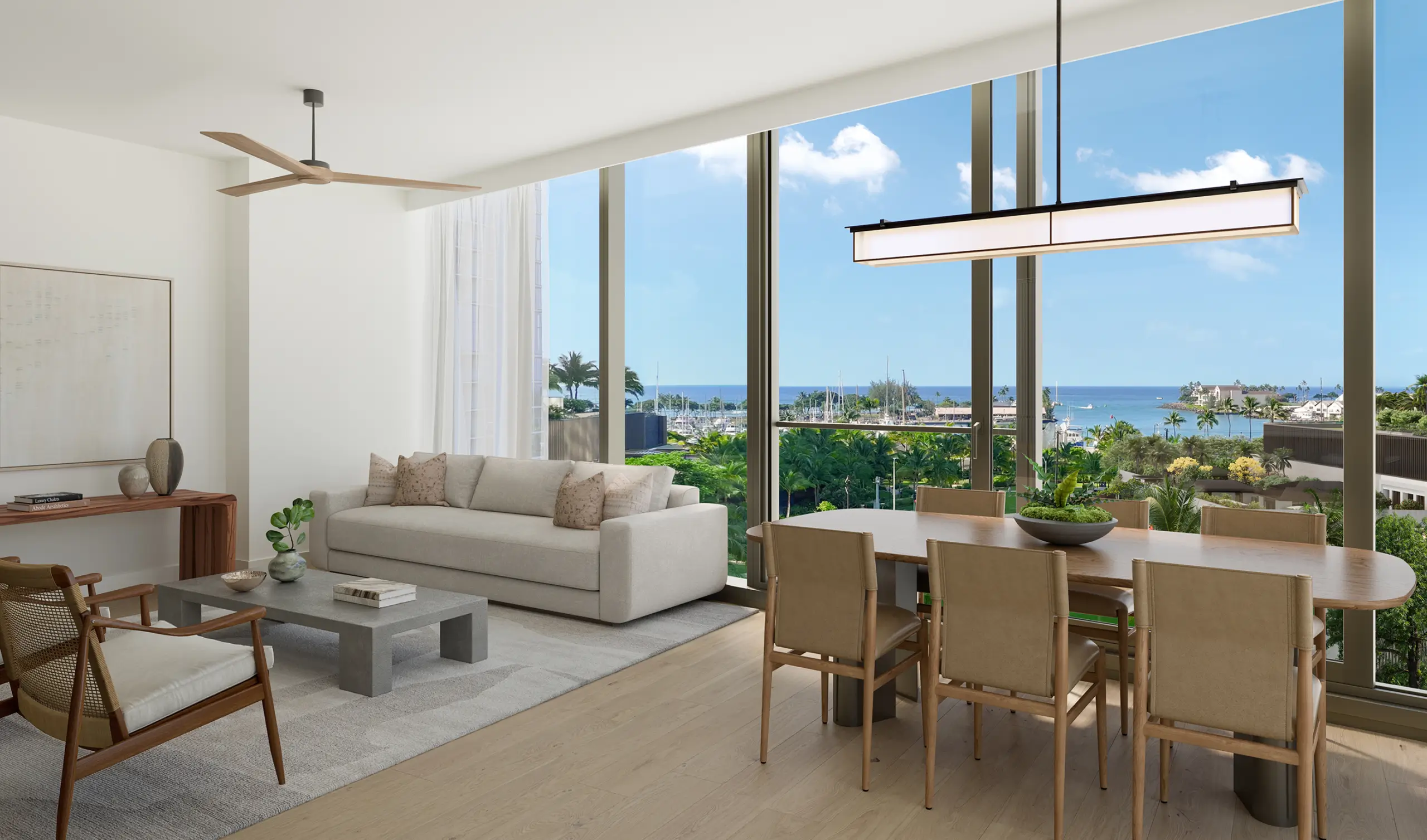 Modern living and dining area with large windows, neutral-toned furniture, and ocean view; wooden floor, ceiling fan, and contemporary light fixture are visible.